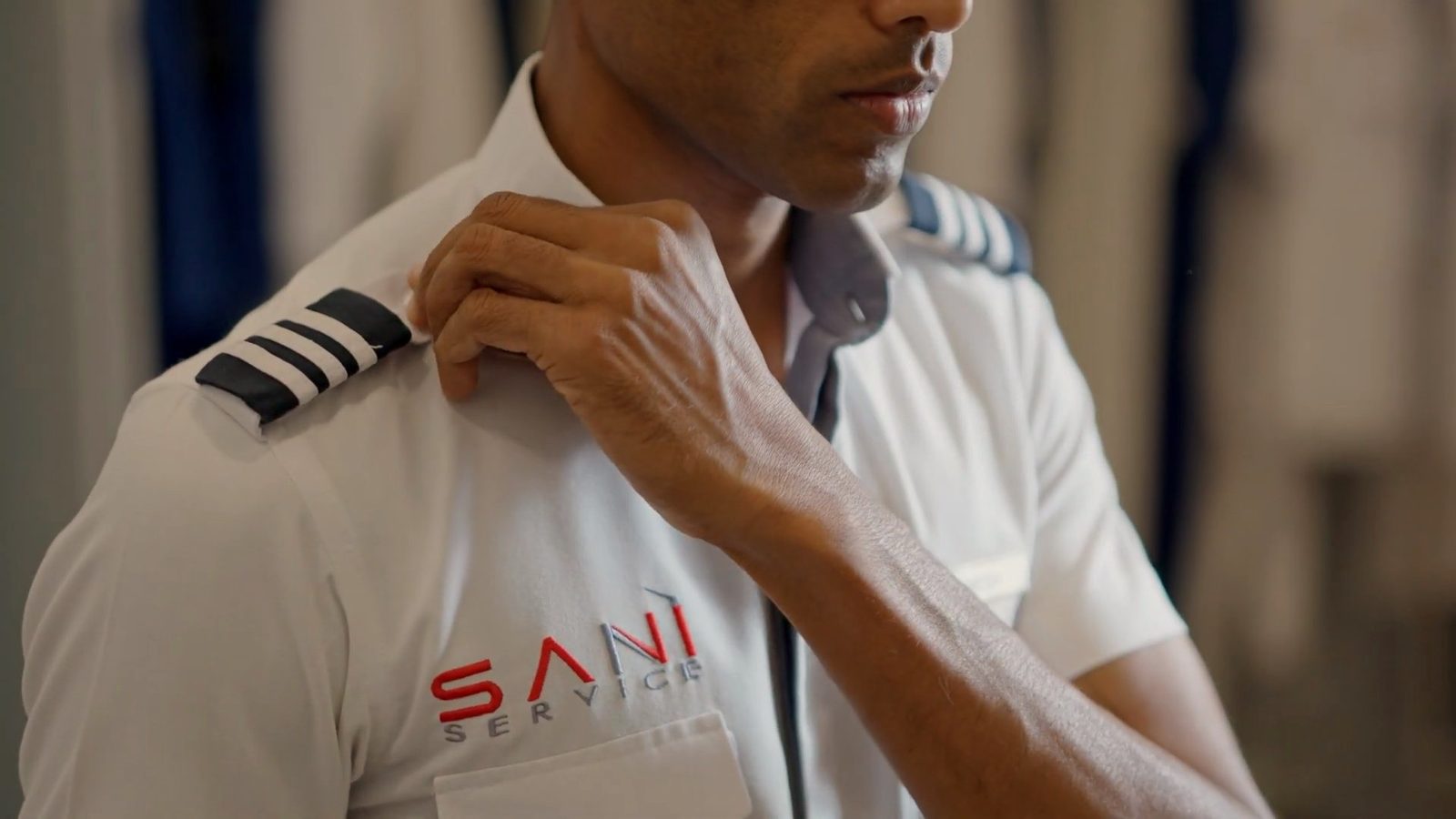 A Saniservice technician in pilot-style uniform with captain's epaulettes